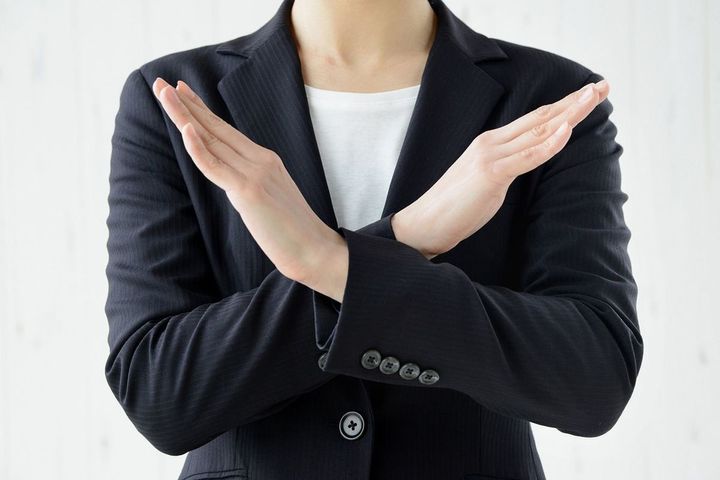 手でバツを作る女性