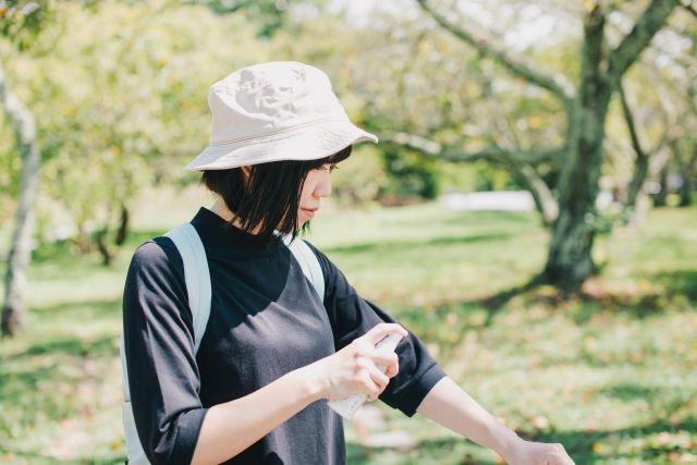 腕に虫除けスプレーをふる女性