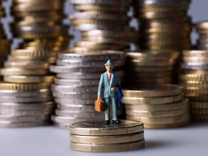 コインの山の上に立っているミニチュアフィギュア