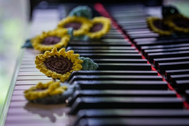 ピアノの鍵盤とその上のひまわりの編み物