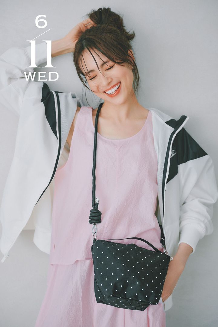 ベビーピンクのタンクとパンツのセットアップにスポーティなブルゾンと黒に白ドットのショルダーバッグを斜めがけした笹川友里さん