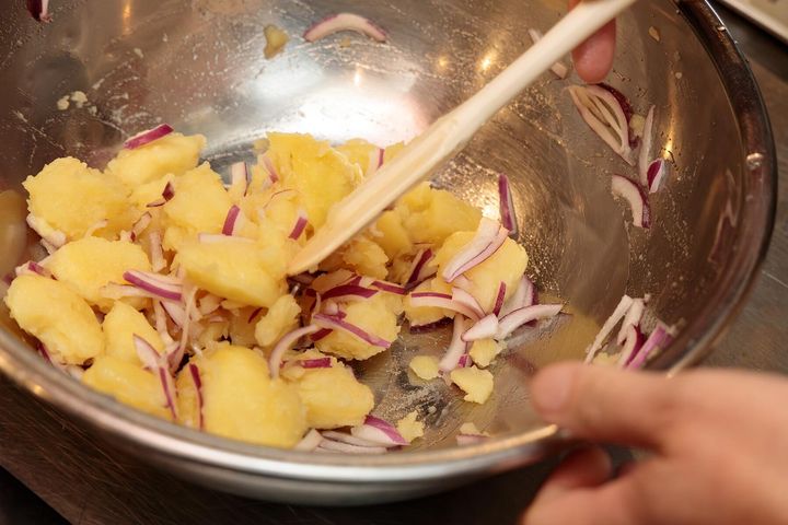 ①の湯をきってじゃがいもが熱いうちに皮をむき、一口大にほぐす。ボウルに入れて塩少々（分量外）をふり、ホワイトバルサミコ酢を回しかけて全体になじませるようによく混ぜ、塩で味を調えたら、③を加えてさっくりと混ぜる。 ※ゆでたてでアツアツのじゃがいもにホワイトバルサミコ酢を染み込ませるのがポイント。