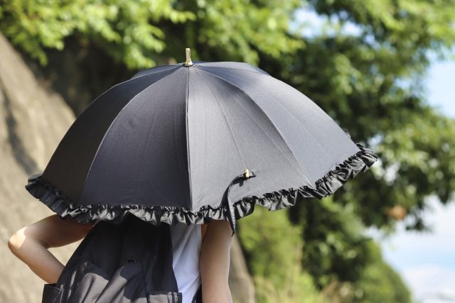 黒い傘をさす女性の後ろ姿 紫外線 熱中症対策