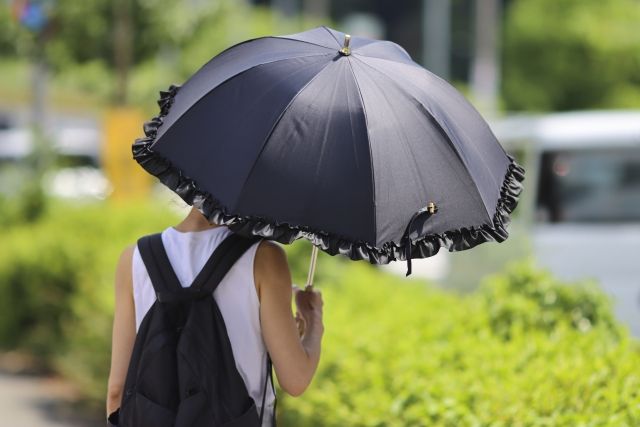 黒い傘をさす女性の後ろ姿 紫外線 熱中症対策