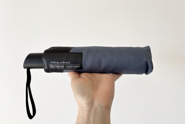 黒い折り畳み日傘を持つ手