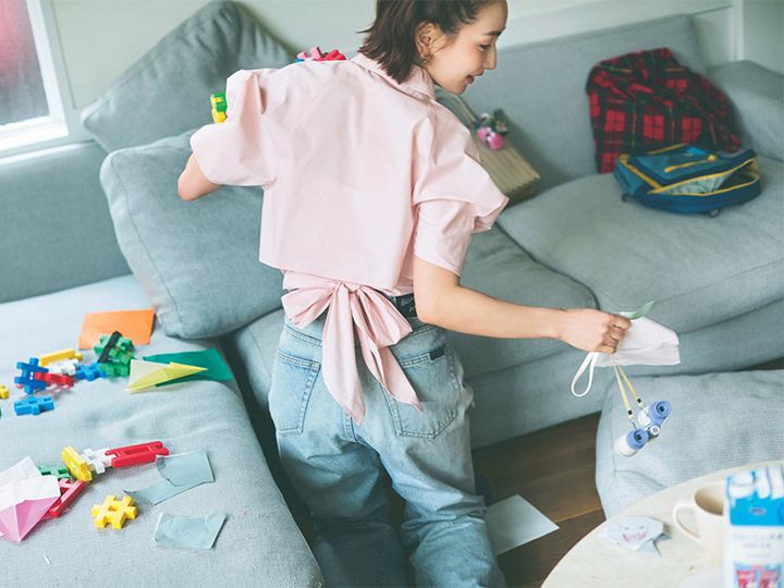 後ろにリボンがついたピンクの半袖シャツとデニムを着て部屋を片付ける辻元舞さん