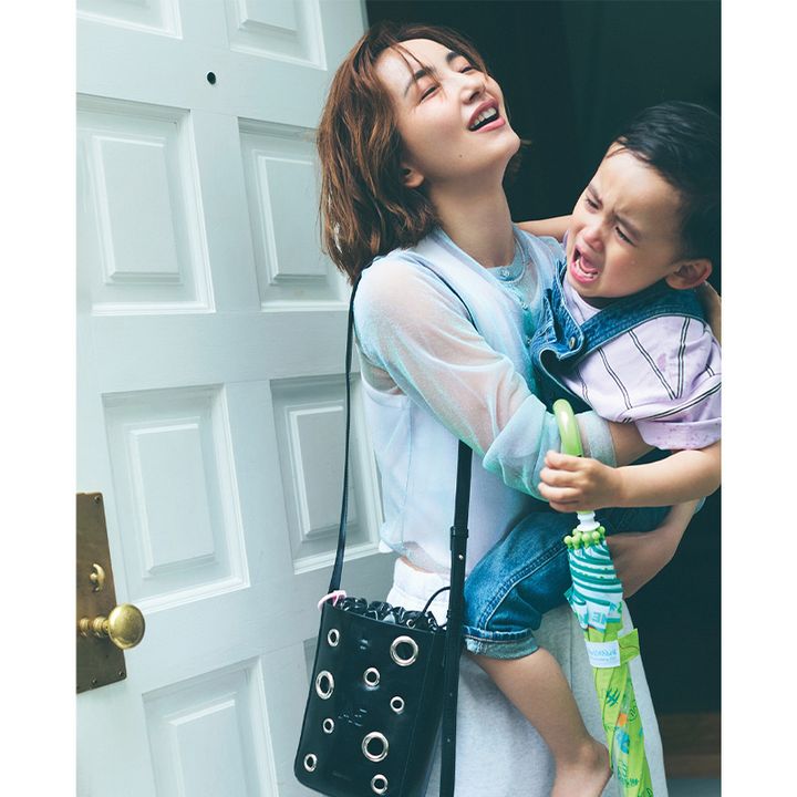 シアー素材のカーディガンとスウェットパンツに黒のショルダーバッグを持って男の子を抱っこした辻元舞さん