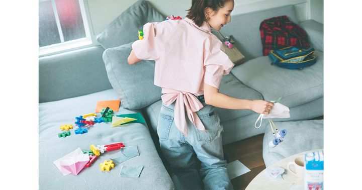 後ろにリボンがついたピンクの半袖シャツとデニムを着て部屋を片付ける辻元舞さん