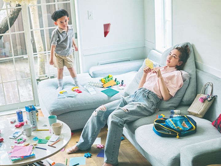 ピンクの半袖シャツとダメージデニムを着てソファに横たわる辻元舞さんと男の子
