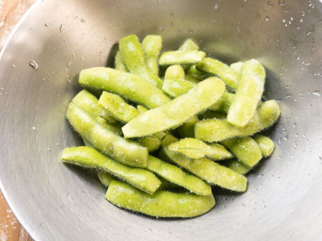 枝豆を流水で洗った後、上下の両端をキッチンバサミ等で切り落とし、塩をまぶして表面のうぶ毛を擦り落とします。