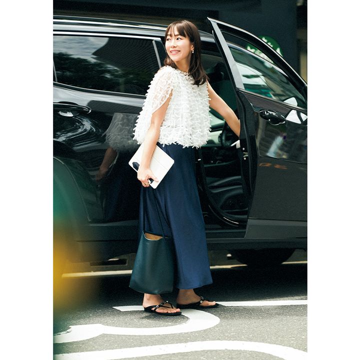 リボンがついたトップスとネイビースカートを着て車に乗ろうとするVERYライター島田さん