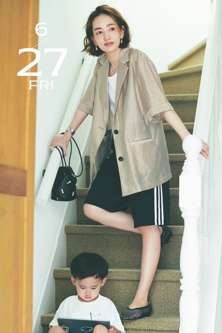 タンクトップとハーフ丈のトラックパンツに半袖ジャケットを羽織ったママと階段に座ってタブレットを見ている男の子