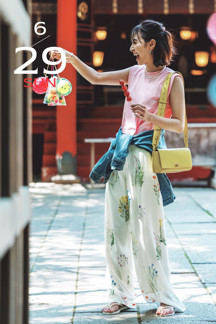 ピンクのタンクトップと花柄パンツにGジャンを腰巻して黄色のバッグやビーチサンダルを合わせたお祭りコーデ