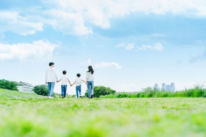 青空を背景に草原を歩く家族