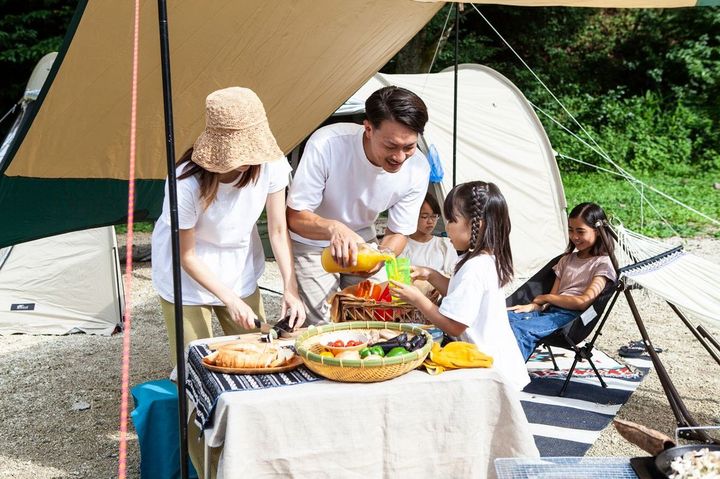 キャンプ場でバーベキューの準備をする家族