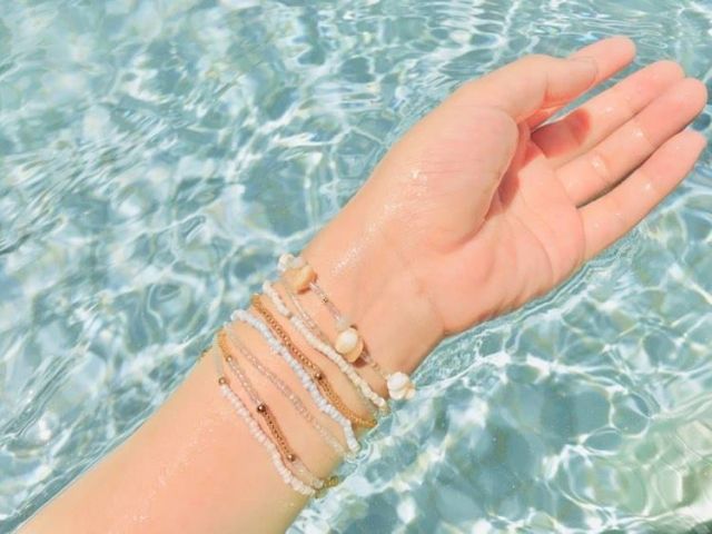 水中に浮かべる腕にブレスレットがいくつかついている様子