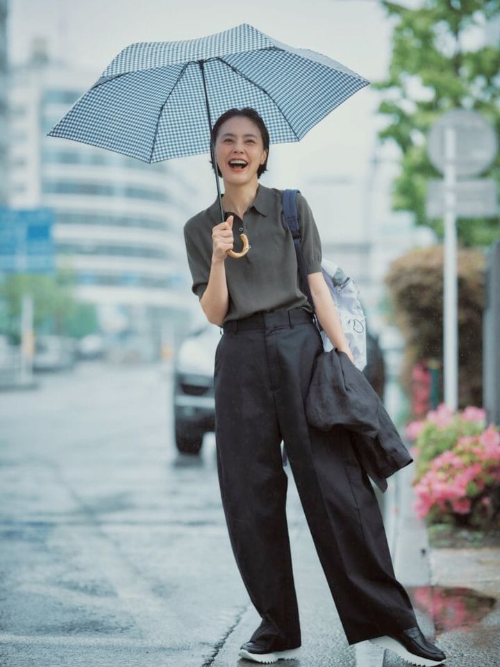 パンツ4万8400円、ポロニット3万800円（ともにハイク／ボウルズ） 手に持ったジャケット1万8700円（カランシエル／シップス インフォメーションセンター） バックパック2万3100円（アコック／ジャック・オブ・オール・トレーズ プレスルーム） 靴4万1800円（プレインピープル／プレインピープル青山） 傘1万5400円（トラディショナル ウェザーウェア／トラディショナル ウェザーウェア ルミネ有楽町店）