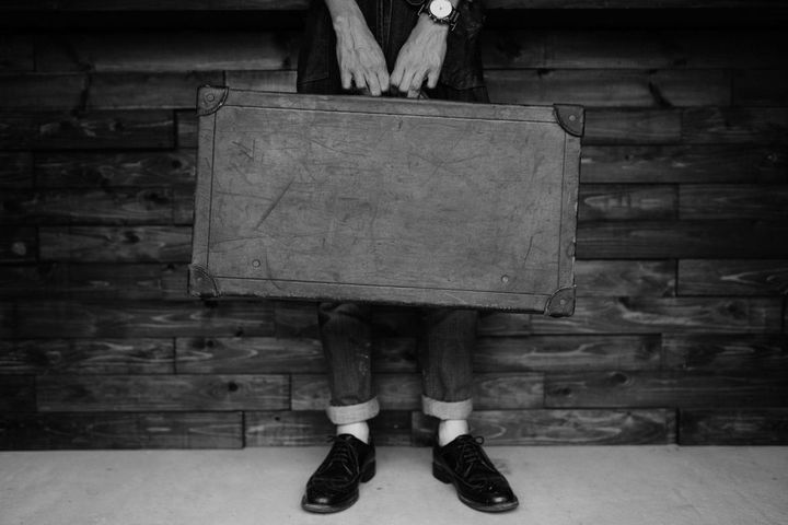 革のスーツケースを持つ男性