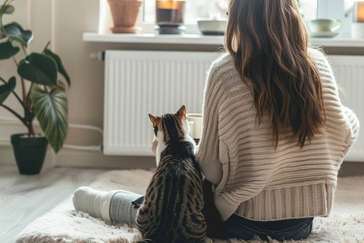 背中を寄せる猫と女性