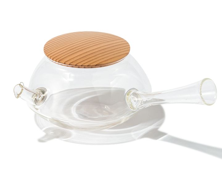 持ち手と注ぎ口は、ガラス管を溶かしながら飴細工のように手作業で作られている。流れるようなシルエットで持ちやすく、注ぎやすい。木製の蓋との組み合わせも美しく、凛とした佇まいに。