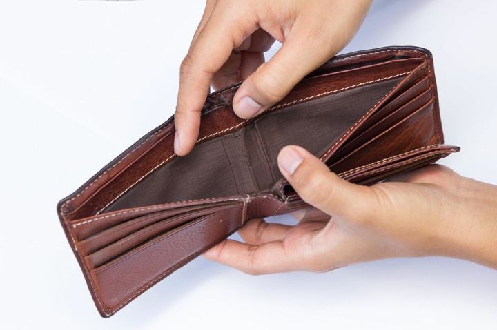 空の財布を開いて見せている男性の手元