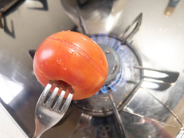 トマトはヘタを取って窪みにフォークを刺し、全体を軽く火で炙る。