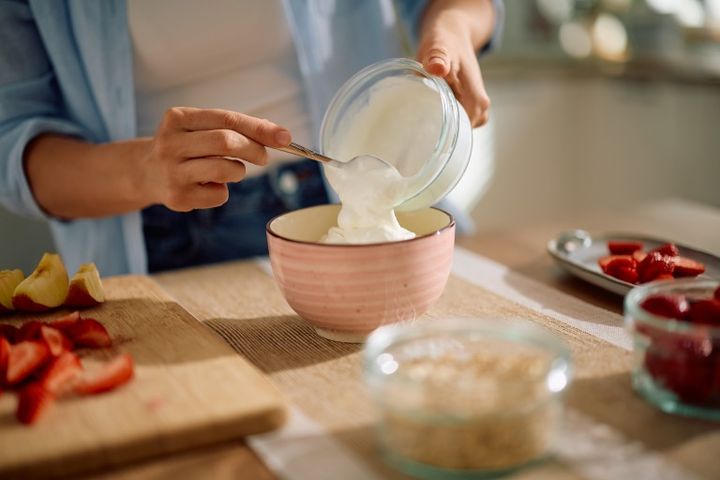 キッチンにいる女性 カット野菜 グリークヨーグルトをボウルに移している様子
