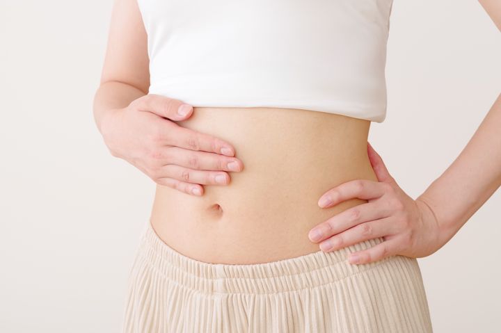 お腹を手で抑える女性 ダイエットイメージ