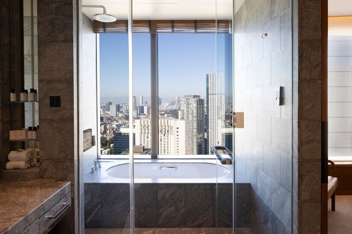 大きな窓から都会の風景を眺めながら、優雅なバスタイム。バスアメニティはオーガニックスパブランド「バンフォード」。