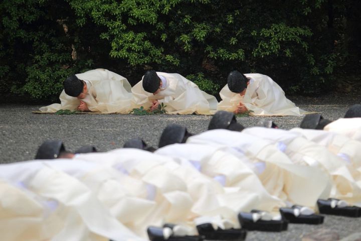 祓い具で祓い清められた後、神職たちは低頭して小さく２度、柏手を打ち、榊に息を吹きかける。