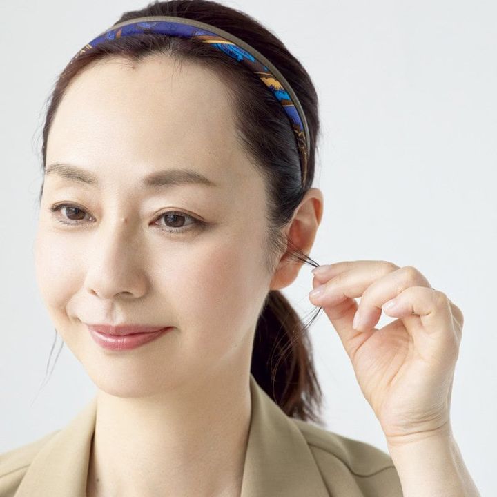 【HOW TO】2．もみあげの毛束を引き出します。この1本があるだけで輪郭が細く見えたりニュアンス感が生まれます。ピタッとまとめたひとつ縛りでも、コンサバになりすぎずにこなれた印象に。
