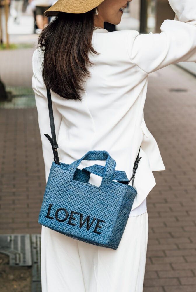 「ロエベ」のブルーのラフィアトートをオールホワイトのポイントに。