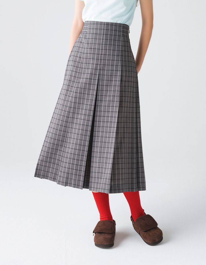 レトロな空気感が新鮮なグレーのチェック柄スカートがお目見え。Aラインと大きなプリーツのディテールによって、はいた時に自然と美しいシルエットが完成する。