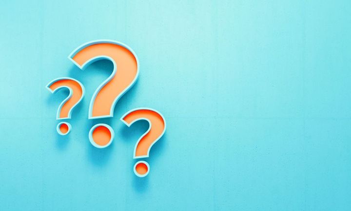 青いコンクリートの壁の背景にオレンジ色の疑問符