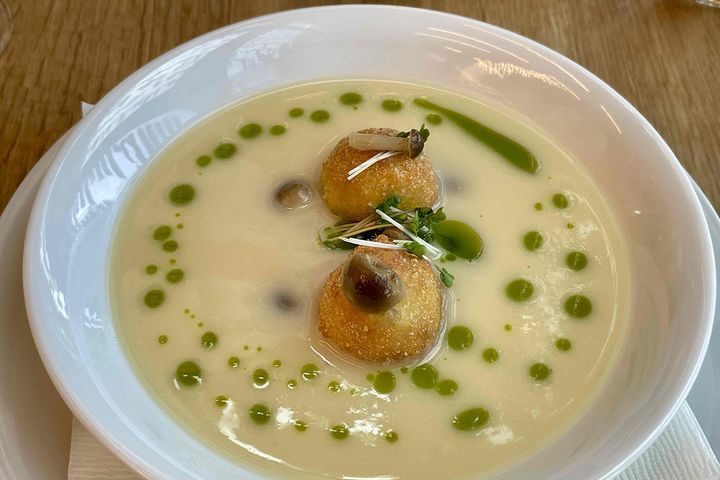 ポロネギとポテトのクリームスープ。緑色のアクセントはネギオイル。スープにクリスピー野菜をからめながら一緒にいただくと、満たされた優しい気持ちに包まれます。