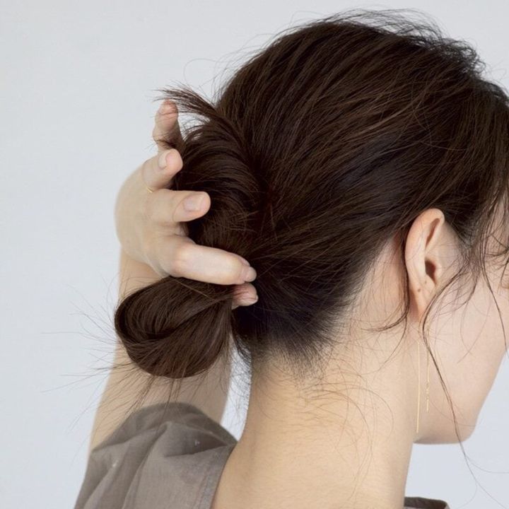 【HOW TO】2．毛先だけ下へ向けて折りたたみます。写真のように縦長の楕円にしましょう。写真を参考にしながら、指を当てているところにゴムをくくって、もう一度縛ります。