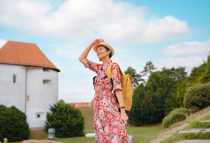 緑豊かでのどかな街をリュックとともに歩く女性