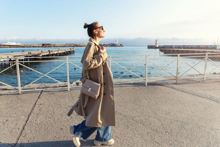 海辺を歩くトレンチコートを着た女性