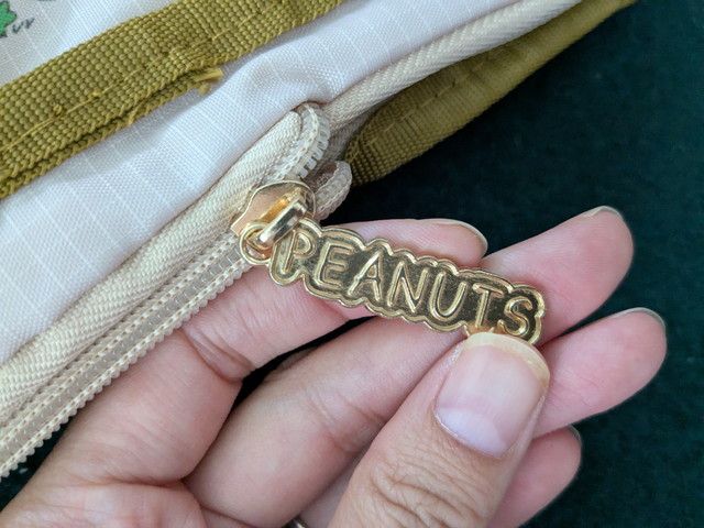 PEANUTSロゴ入りのゴールドチャームとダブルファスナー