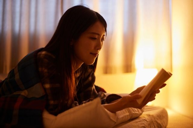 布団を被り読書をする日本人の女性