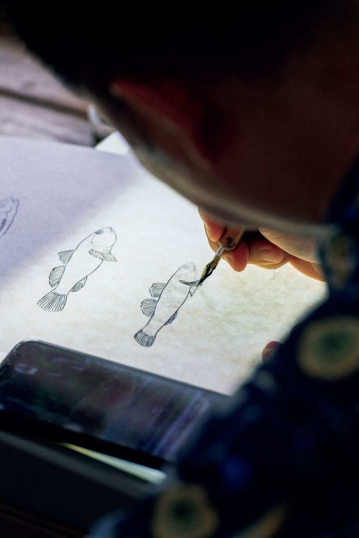 携帯電話で撮った写真を見ながら下書きをし、ペン入れも行う