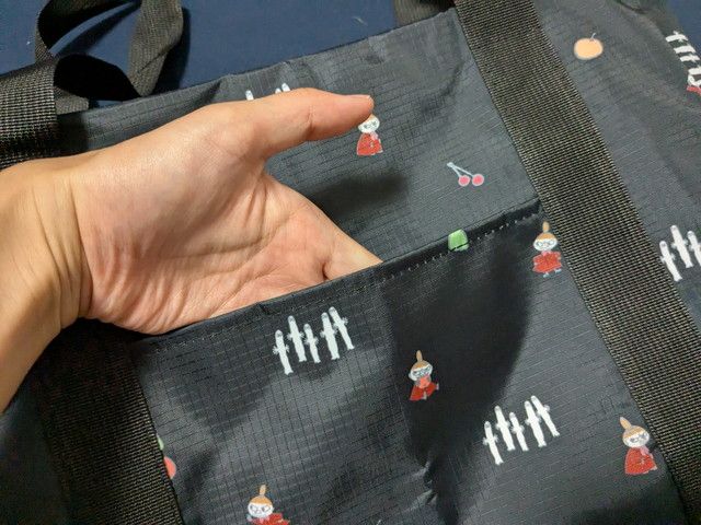 MOOMINボストンバッグの外ポケットを手で示すカット