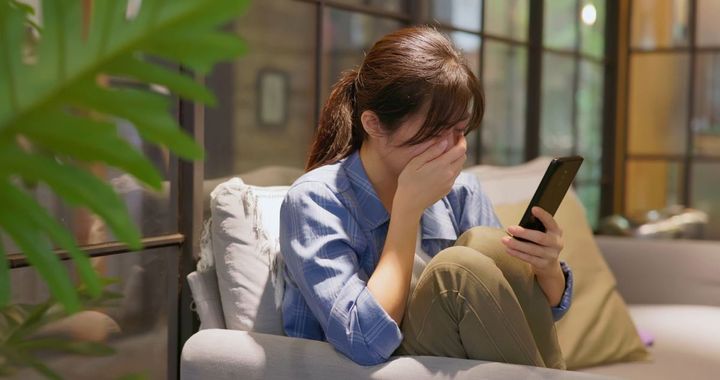 スマホを見て悲しくて落ち込んでいる女性