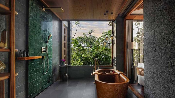 セミオープンのバスルームにチーク材の木彫りのバスタブ（スタジオスイート）。