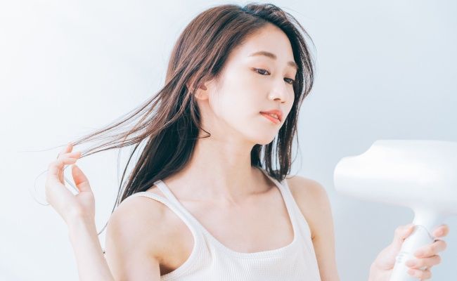 ドライヤーで髪を乾かす女性