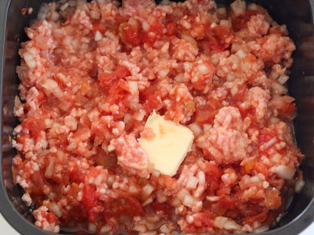 耐熱容器に豚ひき肉、たまねぎ、カットトマト缶、バター、にんにく、ウスターソース、砂糖、塩、こしょうを入れて、全体的にかき混ぜる。