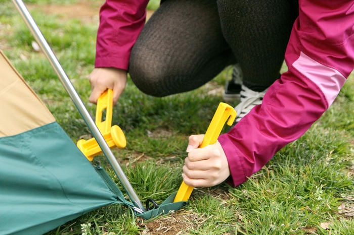 インナーテントをペグで固定している女性の手元