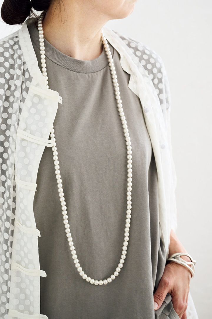 パールのロングネックレスがカジュアルな中にレディなムードを添えてくれる。