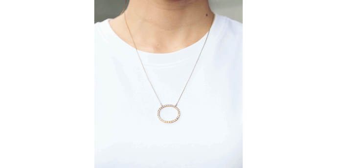 オーバル型のネックレスでミニマルなモノトーンコーデに華やかさを。チェーンが作るVラインが顔まわりをすっきり見せる。