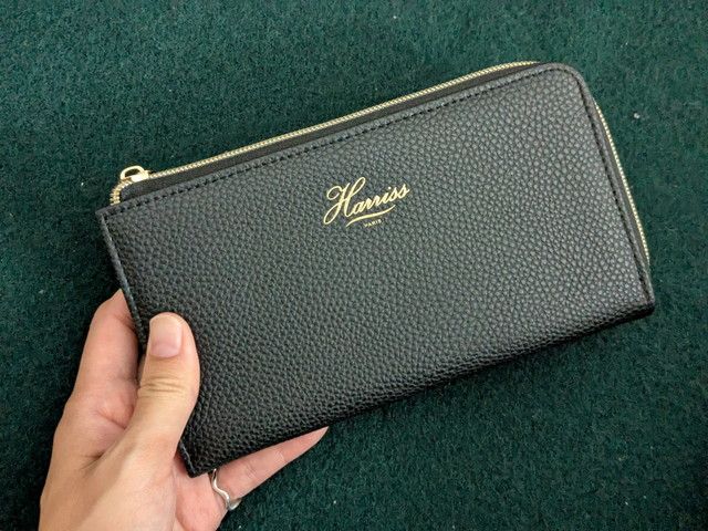 手に持ったHarrissロングウォレット。黒のシボ調にゴールドロゴが映える